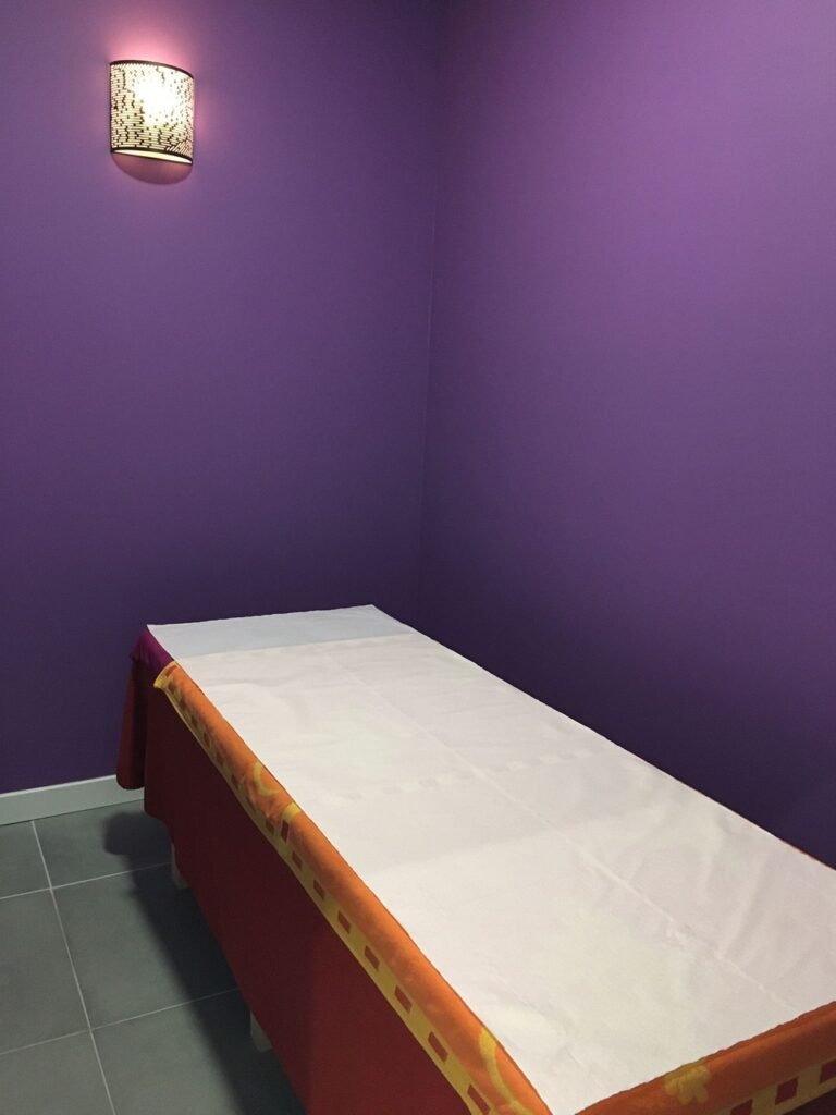 Cabine de massage à l'éclairage tamisé, table drapée de rouge et d'orange