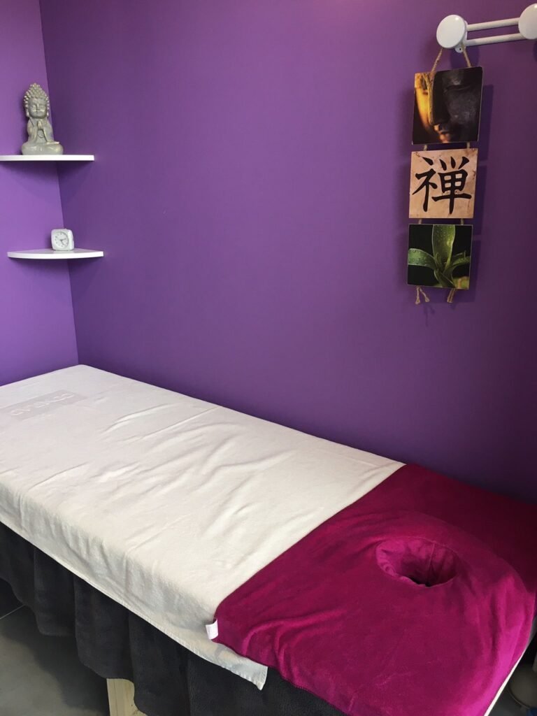 Cabine de massage aux murs violets, statuette de Bouddha et calligraphie zen